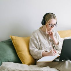 lady writing in a notebook with her laptop open